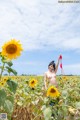 A naked woman standing in a field of sunflowers.