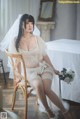 A woman in a wedding dress sitting on a chair.