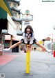 A woman in a school uniform is doing a trick on a pole.